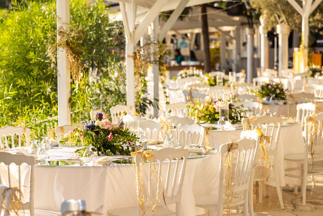 Beautifully arranged outdoor wedding reception with floral centerpieces and white decor.